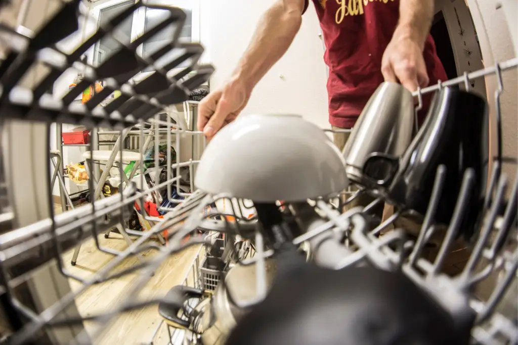 Lave-vaisselle ouvert avec des assiettes encore sales dans le panier inférieur